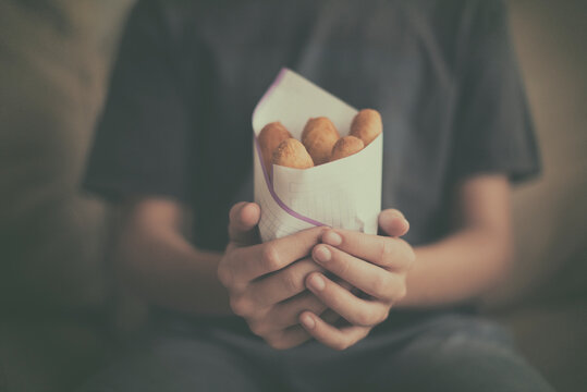 Close-up of a teenage boy holding a bag of traditional Jamaican deep fried bread (Jamaican festivals)