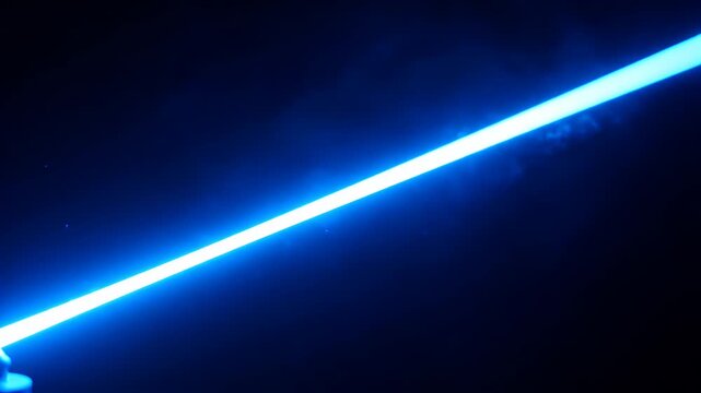 A bright blue lightsaber blade cuts through the darkness, with small sparks or particles illuminated.