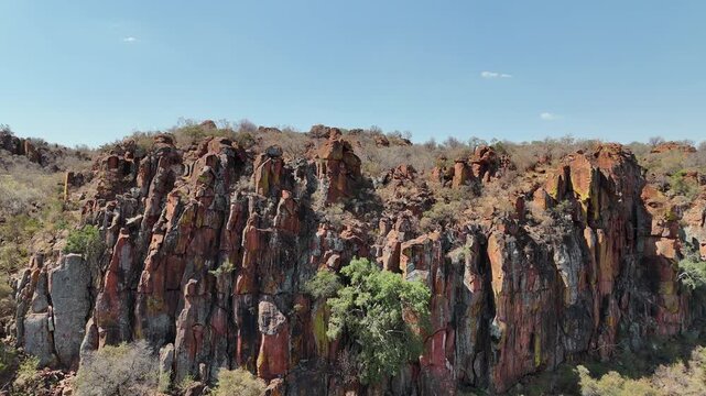 Cinematic aerial footage of majestic red sandstone cliffs and rugged escarpments in the arid wild savanna of Namibia, Africa. Epic geological formations.