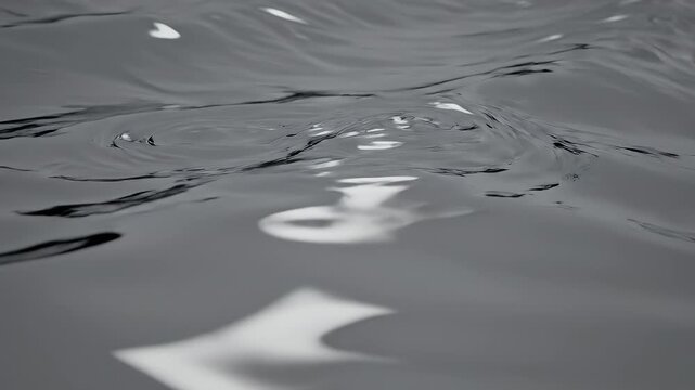 Close-up view of dark water surface with gentle ripples and light reflections.