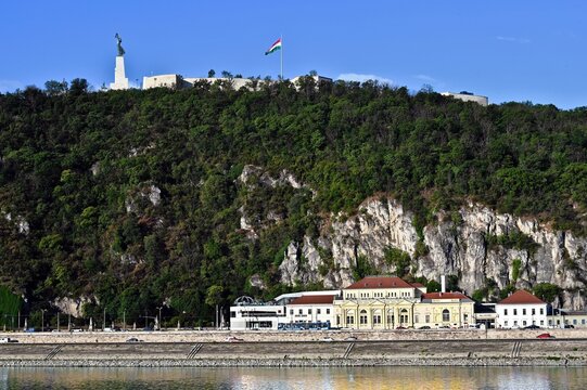 panoramic view of the newly renovated Citadel in Budapest, Hungary. old stone fort and castle. the statue of Liberty and large Hungarian flag on top of white stone cliffs. the Danube river with boats