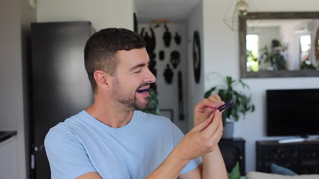 Smiling adult man applying blue teeth whitening strips