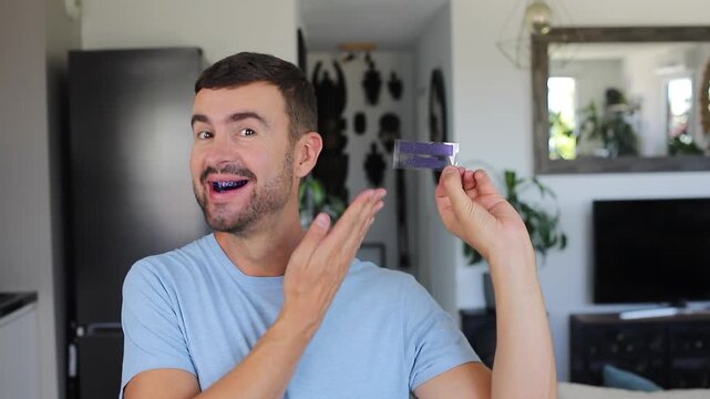 Smiling adult man applying blue teeth whitening strips