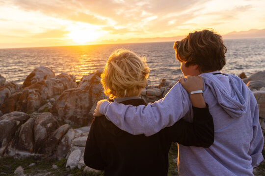 two boys exploring and hiking the spectacular rocky coastline of DeKelders, South Africa at sunset
