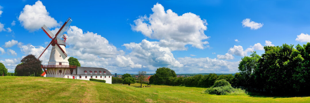 Panoramic view of historic Dybbol Mill near Sonderborg with open landscape, dramatic clouds, blue sky and summer atmosphere.