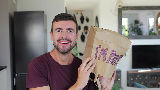 Man covering head with a funny paper bag where he wrote a cute message 