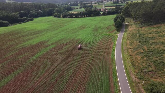 Agricultural tractor applying pesticide or fertilizer to young corn crops