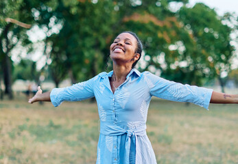 Happy young black woman meditating and daydreaming and relaxing and having fun in nature outdoors
