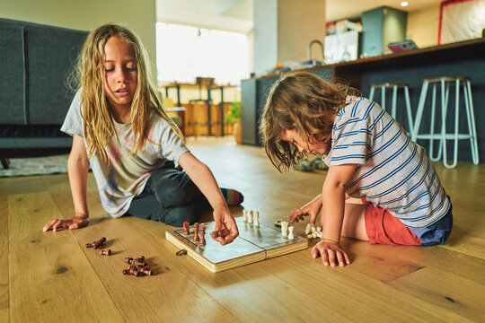 Two boys playing chess on the living room floor