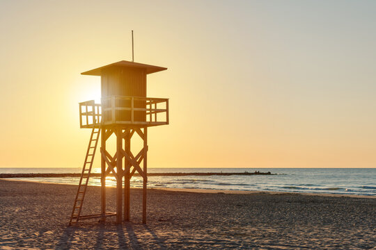 Wooden lifeguard tower on sandy beach at sunrise