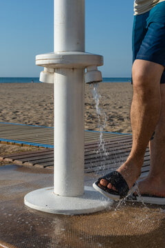 Vertical close up of man washing feet at beach foot wash