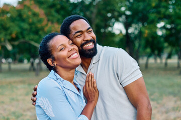 Fototapeta premium Portrait of a young black couple, portrait of a woman with her husband or boyfriend in park outdoors. Support love and care concept