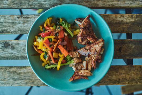 Grilled chicken and stir-fry vegetables served in a turquoise bowl