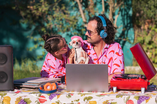 Father and daughter djs playing music at a summer party with their chihuahua dog