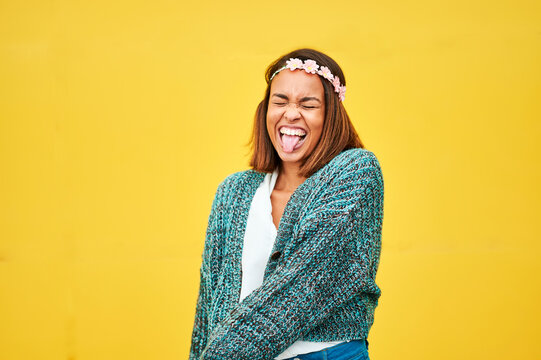 Woman sticking out tongue with yellow background