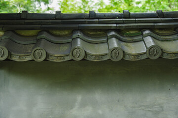 新緑を背景にした漆喰壁と葉の紋様入り軒丸瓦 © kikisora