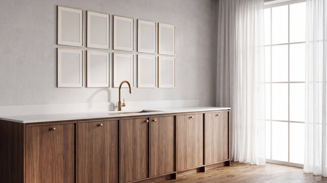 A bright, minimalist kitchen interior featuring dark wooden cabinetry, a white countertop, gold fixtures, and a gallery wall with ten empty picture frames.