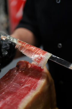 experto en corte de jam&oacute;n ib&eacute;rico cortando una loncha de jam&oacute;n que sujeta en el cuchillo