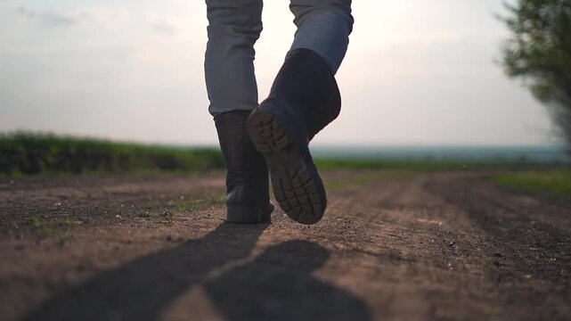 Walking along quiet dirt road at sunset, man leaves long shadows behind. Farmer slowly walks steady rhythm. Each step marks dirt path as outdoor scene unfolds. Walking motion repeats in natural rhythm