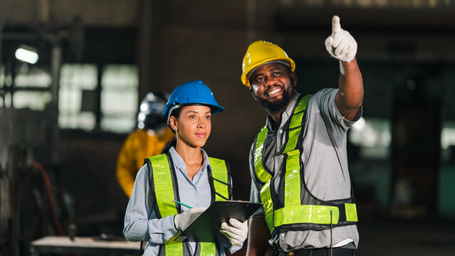 Engineer worker hard hat safety vest construction factory team clipboard glove pointing, diverse industrial team wearing protective gear review clipboard while worker point upward factory workplace