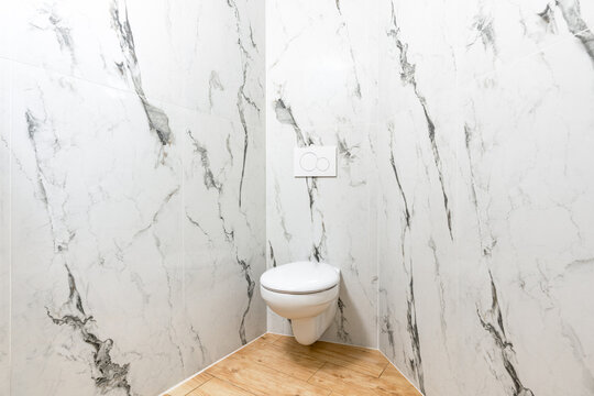 Modern bathroom interior with white marble walls and toilet