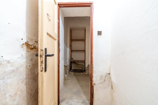 Old doorway revealing neglected storage room with peeling walls