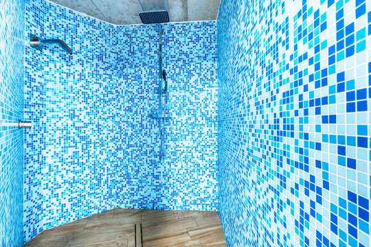 Modern bathroom shower with blue mosaic tiles and wooden floor
