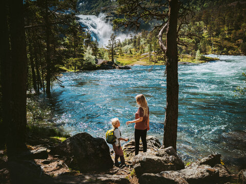 Family travel in Norway - mother and child hiking together, mom and daughter on camping vacations tour in Husedalen valley outdoor summer activity parent and kid enjoy nature waterfall and lake view
