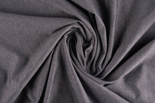 Close-up top view of heather gray dry-fit fabric with a folded, twisted polyamide texture.