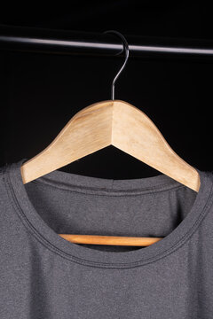 Editable mockup of a printed logo on a fitted heather-gray t-shirt (screen-printed), close-up on the collar, hanging on a hanger.