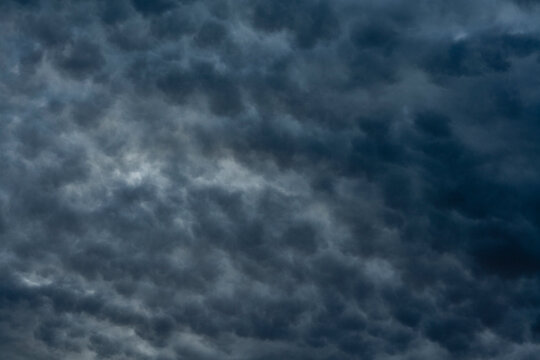 Dramatic dark storm clouds filling the sky texture background. Dense layer of dark grey and blue overcast clouds in stormy sky creating dramatic climate background