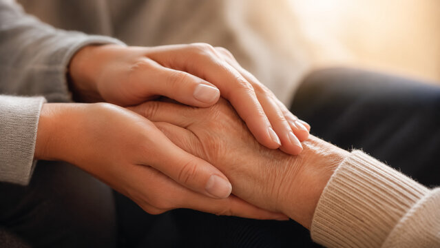 Young person holding elderly hands. Caring caregiver providing comfort to a senior person.