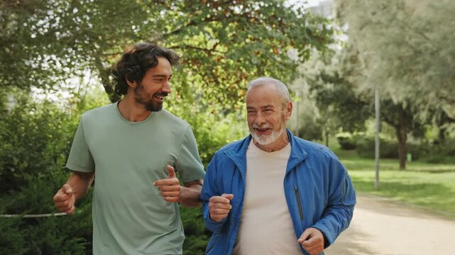 Senior father and young son running together doing sport training outdoors urban park 