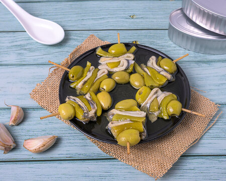 Gilda pintxos with olives, anchovies and peppers on a rustic plate, highlighting traditional Basque flavors in a vibrant food composition