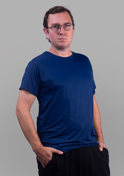 Studio photo of a 40-year-old white Brazilian male model wearing glasses and a blue short-sleeved polyamide dry-fit shirt.