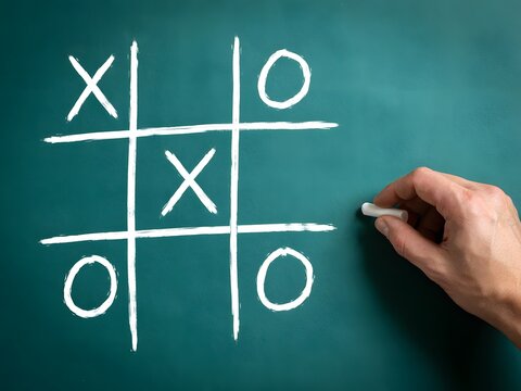 Hand drawing tic tac toe game on chalkboard with chalk