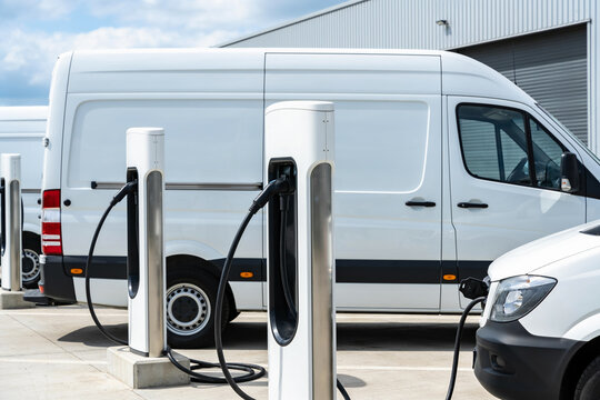 Electric vans charging at a modern charging station in an outdoor lot