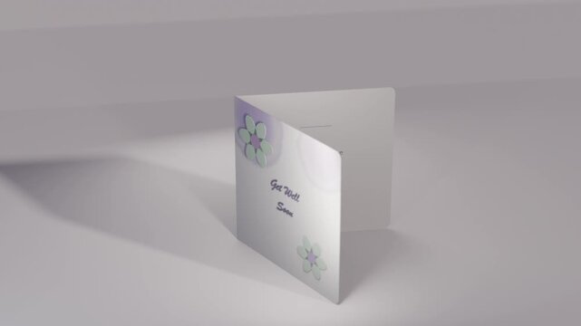 Rotating folded square card opening on desk by animation, revealing Get Well text, pastel florals