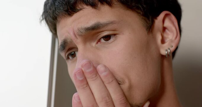 African American man bringing hand to mouth reacting to bad news near window wearing watch