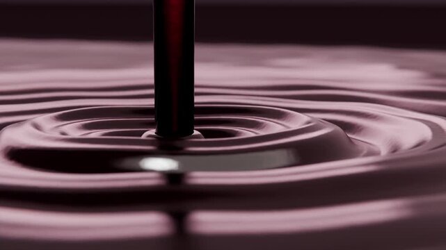 Dropping thin stream striking glossy deep maroon pool on table forming mound and rippling outward