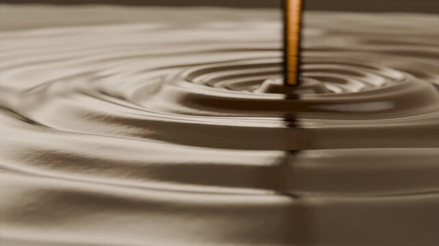 Pouring golden stream hitting glossy brown syrup in shallow tray studio close-up, forming ripples