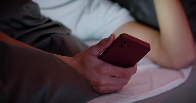 African American man receiving message, reading red phone in bed, frowning, rubbing hair