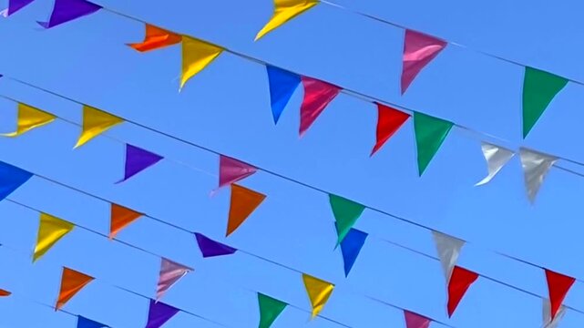 Multicolored triangular small flags to celebration party against blue sky. Street holiday concept,4K.