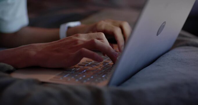African American man 20s starting study in bedroom, typing on laptop, wearing white wrist device