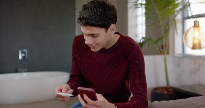 Man holding card, tapping phone after card prompt, verifying payment in bathroom while smiling