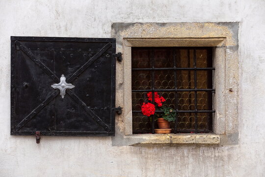 Red pelargonium in the barred, black iron shuttered, open window of the XVII c.Martinova hisa on Mestni trg square west side. Skofja Loka-Slovenia-147