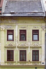 Fototapeta premium Chipped lime-yellow facade, windows decorated with cream-white carved aprons and gables, house on Mestni trg square E side. Skofja Loka-Slovenia-154