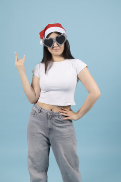 Happy young woman in red santa hat pointing fingers to the side wall