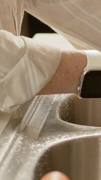 Vertical video: Reacting to water, arm and hands rinsing kitchen sink, in striped top, white watch