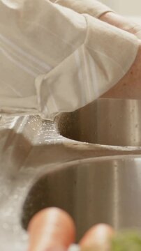 Vertical video: Seeing drops, wrist rolling cuff to keep sleeve dry, wiping kitchen sink rim, watch